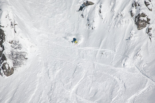 Extreme freeride skier dropping from a steep rocky ridge in a high 