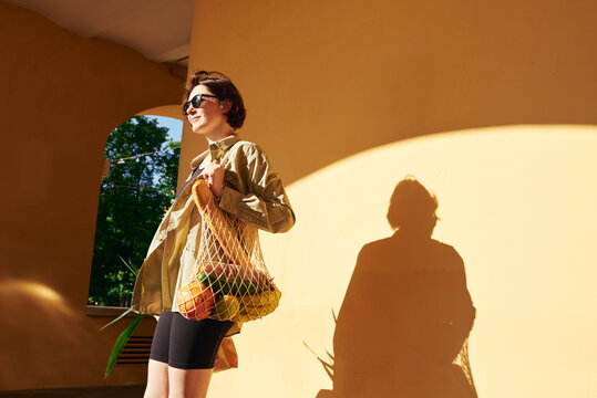 Woman carries a mesh bag filled with fruits 