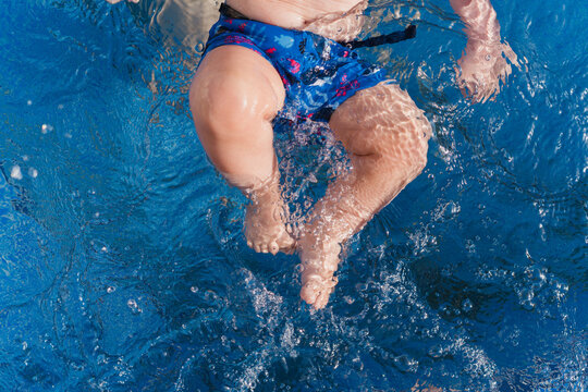 Baby playing in blue water learning to swim
