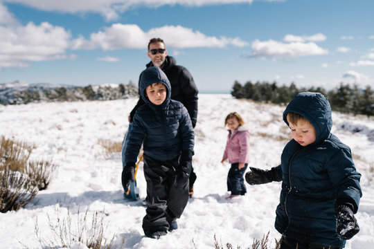 Father and children walking through snow during winter activities