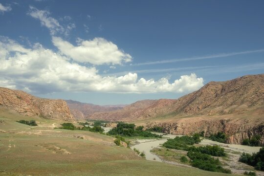 Scenic valley of Chilik River in Kazakhstan with rolling hills, winding river, and copy space. Ideal as a background for travel, environmental, and outdoor adventure marketing campaigns.