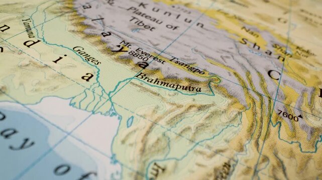 gliding view over tibet, ganges and brahmaputra on printed atlas map
