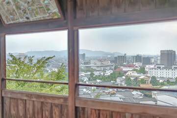 Fototapeta premium 阿智神社から望む白壁の伝統家屋と広大な近代的都市の景色/The Scenery of Traditional White-Walled Houses and the Vast Modern City Viewed from Achi Shrine