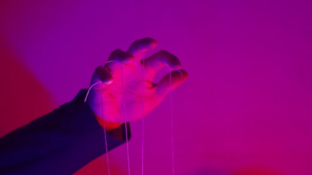 Hand with Puppet Strings in Neon Pink Light &mdash; Control and Manipulation Concept