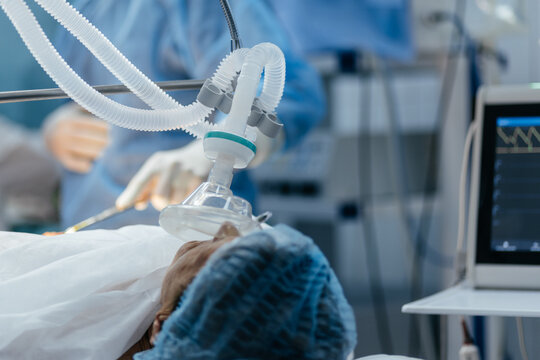 Patient under general anesthesia with a breathing mask during surgery in a modern hospital operating room