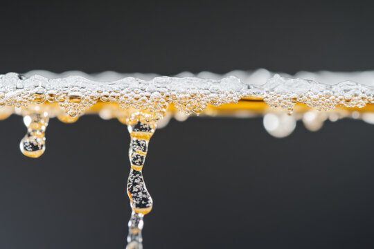 Close-up of water and amber-colored liquid flowing with bubbles, background