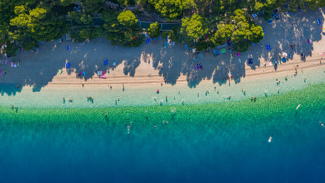 Top-down aerial view of Punta Rata beach in the morning with long shadows in Brela, Croatia