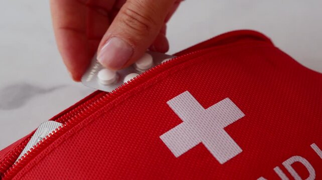 Close up of woman placing medication into first aid kit for emergency preparedness