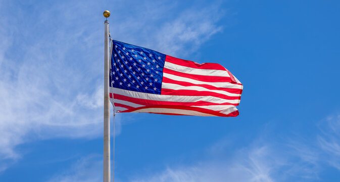 American flag waving in the wind on a flagpole against a blue sky with clouds in Key West, Florida