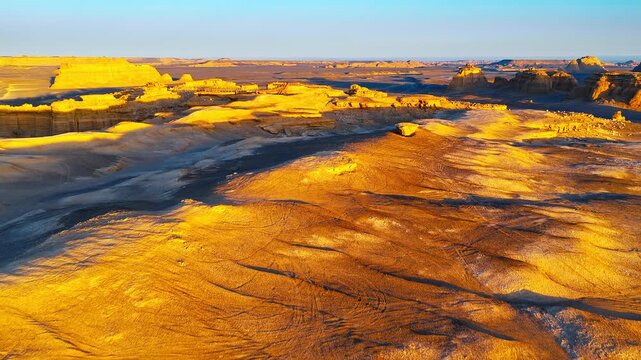Aerial view of golden yardang landforms illuminated by the setting sun in Xinjiang, China.