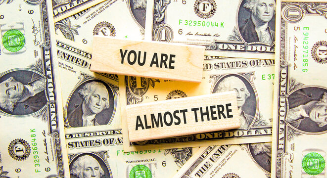 You are almost there symbol. Concept words You are almost there on beautiful wooden blocks. Beautiful dollar bills background. Business You are almost there motivational support concept. Copy space