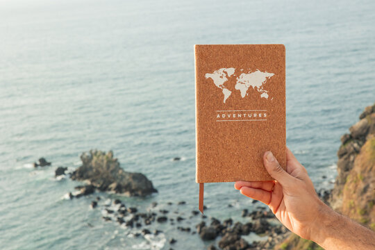 Hand holding travel planning notebook dreaming of adventure