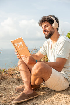 Man enjoying digital detox reading travel journal on cliff