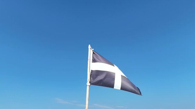 St Piran's Flag of Cornwall Waving in Wind Against Clear Blue Sky