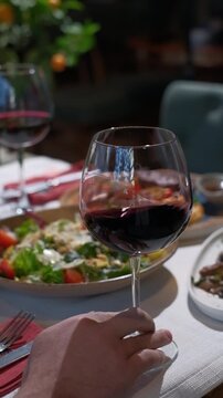 Hands, person and swirl red wine in glass for taste testing, quality control and sensory ritual. Customer, inspection and alcohol for aroma, balance flavour and evaluation process to prepare palate