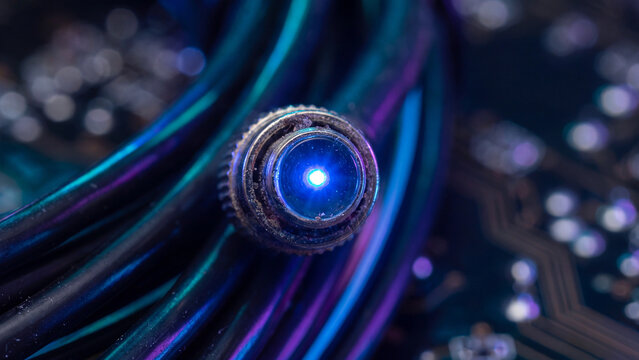 Cable connector glows with a bright blue LED light against a dark, intricate circuit board background.