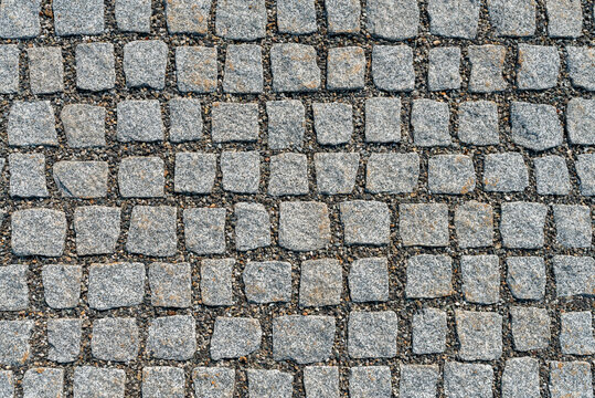 Granite sett paving with gravel joints, gray square stone cobblestone texture background top view
