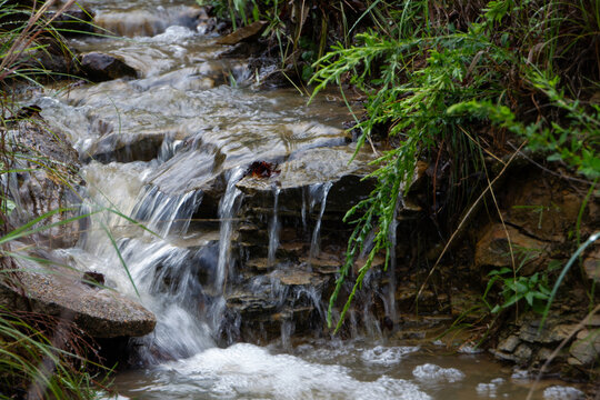 Water streams down the rocky mountain terrain after the rain