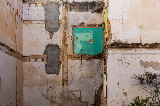 Partially demolished wall exposing weathered masonry and a surviving section of green ceramic tiles, illustrating urban decay, renovation and architectural transformation.