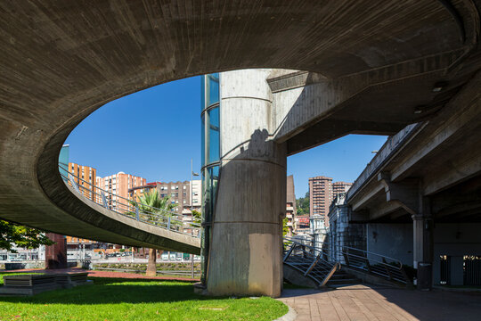 Modern concrete pedestrian overpass with curved ramps and geometric forms in Bilbao, Spain, highlighting contemporary urban architecture and infrastructure