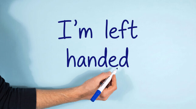 Person writing i'm left handed on blue board with marker