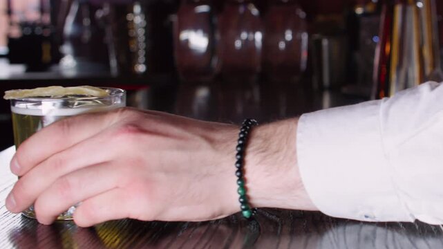 Drink presentation. Alcohol cocktail. Unrecognizable man bartender hand serving modern cold beverage using glass on bar counter.