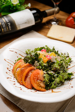 Fresh tomato salad with greens on white plate