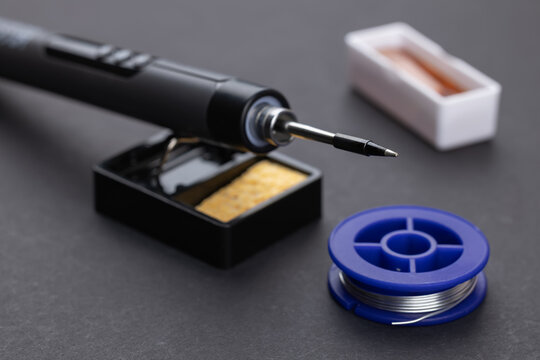 soldering iron with solder and rosin on dark background
