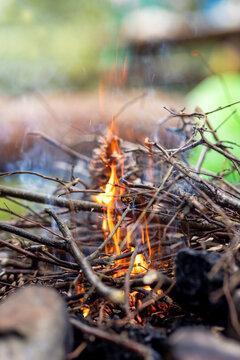 A pile of firewood burning with orange and yellow flames. Making a fire for roasting, grilling, baking and cooking with branches. Dangerous fire