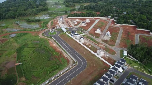 Aerial view of a new modern residential housing estate development project with paved roads and cleared land in a green landscape