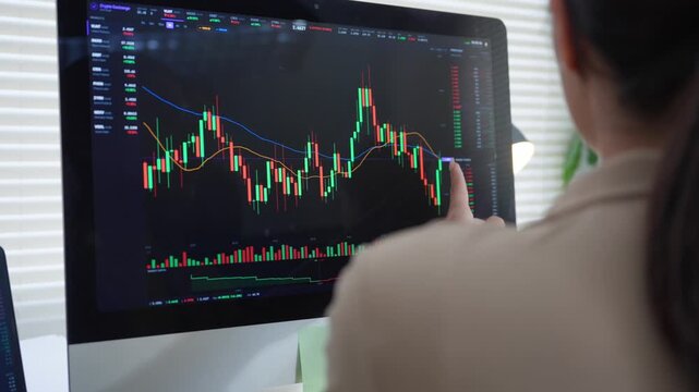 Financial analyst studying cryptocurrency chart on a computer monitor while pointing at the price data
