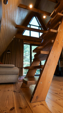 Cozy wooden cabin interior with a unique staircase and triangular window