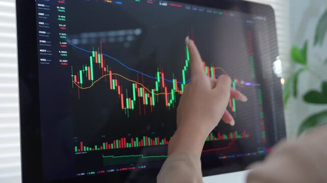 Female stock trader analyzing financial candlestick chart on computer screen for investment opportunities