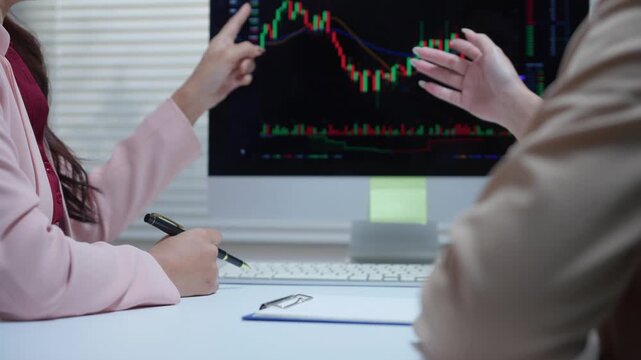 Financial advisors analyzing stock market charts and discussing investment strategy for trading cryptocurrency on a computer screen