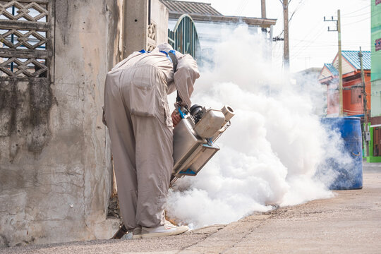 Worker spraying chemical fog for mosquito control in residential area. Prevention of dengue fever and malaria disease concept.