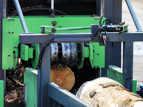 Industrial log processing machine cutting timber in a modern sawmill production facility
