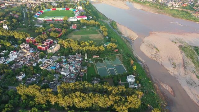 Aerial establishing shot of Tawi river, Jammu City and MA Stadium during golden hour.
