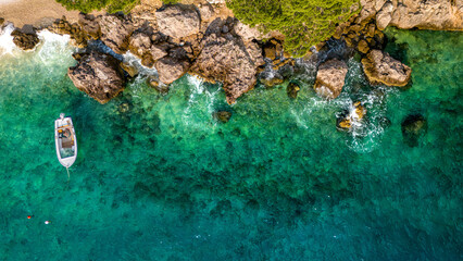 Top-down aerial view of a small boat anchored by the rocky cliffs in Brela, Croatia © Light&Lens