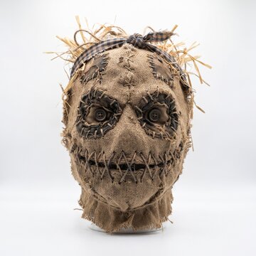 Halloween A creepy scarecrow mask with stitched features, button eyes, and a bandana is displayed against a plain background, evoking a sense of Halloween and rustic charm.