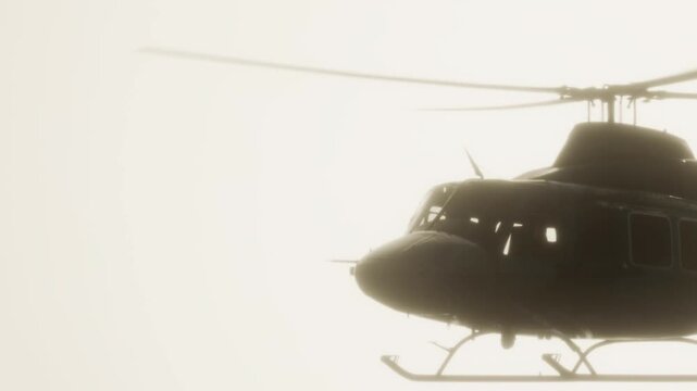 A helicopter moves through thick fog above a city. The bright sky gives a pale glow, while the rotor blades create a distinct silhouette against the light.