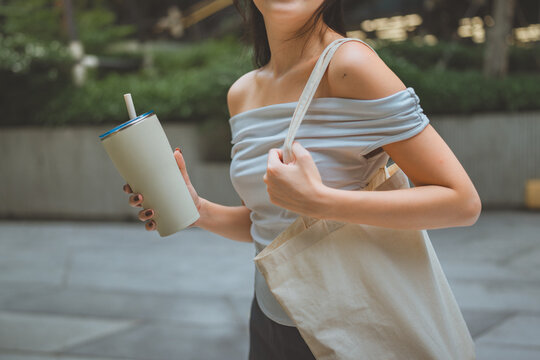Close up woman show reusable glasses of water in her hand with cloth bag, Reusable shopping bag. Natural material. Zero waste. Plastic free. Eco friendly concept, save the earth.