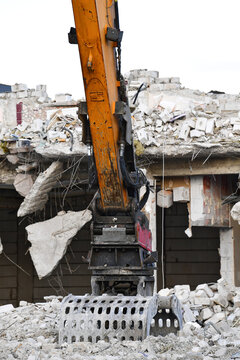 Excavator demolishing a building; professional demolition of building structures