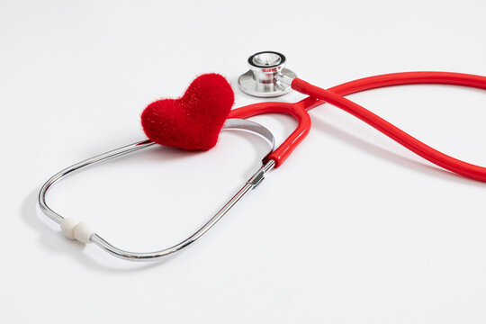 Red stethoscope and plush red heart on white background. Medical layout with copy space, cardiology checkup concept, healthcare insurance template, cardiovascular exam, life safety, wellness.