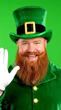 Man in Leprechaun Costume Smiling and Waving on Green Background.