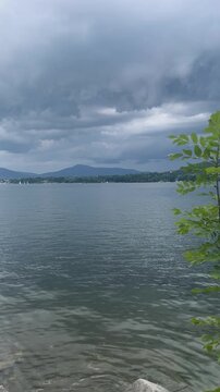 Vertical HD video of dramatic storm clouds over a mountain lake with original relaxing water splashing audio