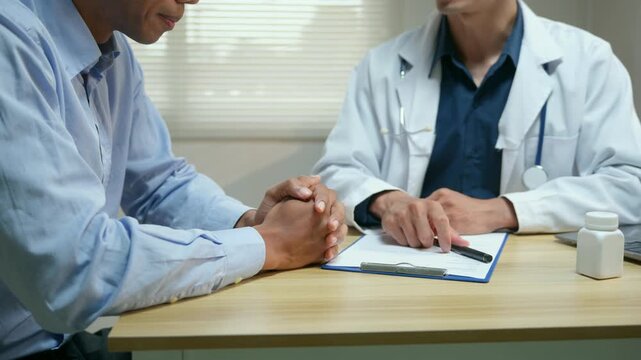 Compassionate doctor comforting a worried male patient with bad news about his medical examination results in the hospital clinic