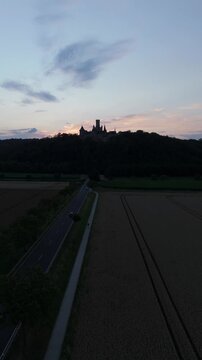 Aerial Vertical video of Marienburg Castle on a ridge at sunset above a road
