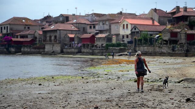 Woman Walking through the Traditional Granite H&oacute;rreos and Coastal Architecture along the Narrow Streets of Combarro in Poio, Galicia, Spain