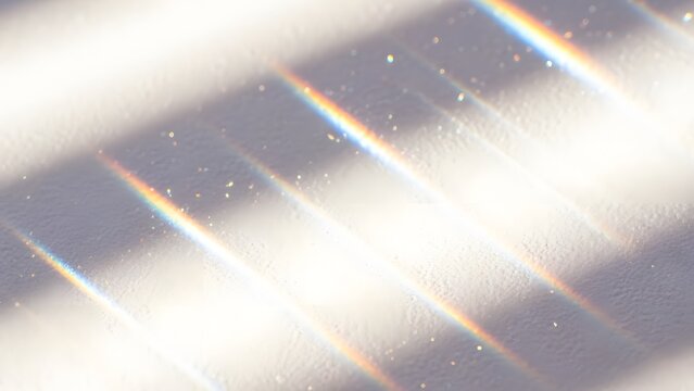 Dynamic diagonal rainbow light streaks, a beautiful prism effect and subtle textured shadows on a white surface.