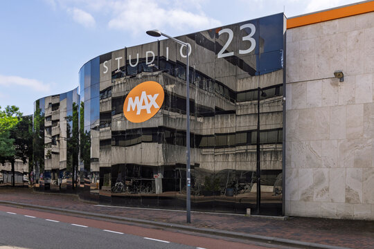 Hilversum, Netherlands - July 13, 2026: The orange oval logo of the Dutch broadcaster Omroep MAX on the glossy black reflective glass facade of Studio 23 at the Media Park broadcasting complex.